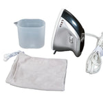 A compact electric steamer iron set on a white background, including a silver and black steamer head, white cord with plug, a translucent plastic cup, a light gray drawstring pouch, and a white fabric cleaning cloth.
